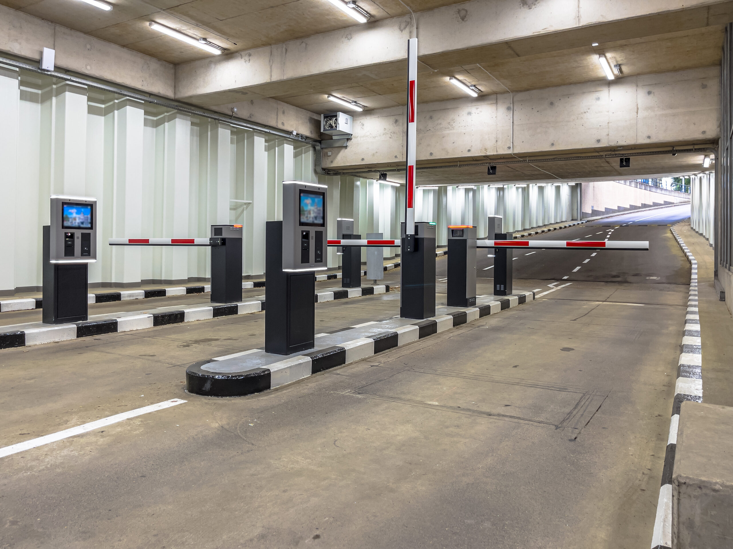 Modern underground parking entrance with automated barriers and contactless payment terminals