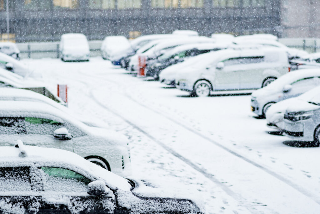 Snow-covered cars in a busy parking lot during winter, highlighting the need for reliable unattended parking payment systems.
