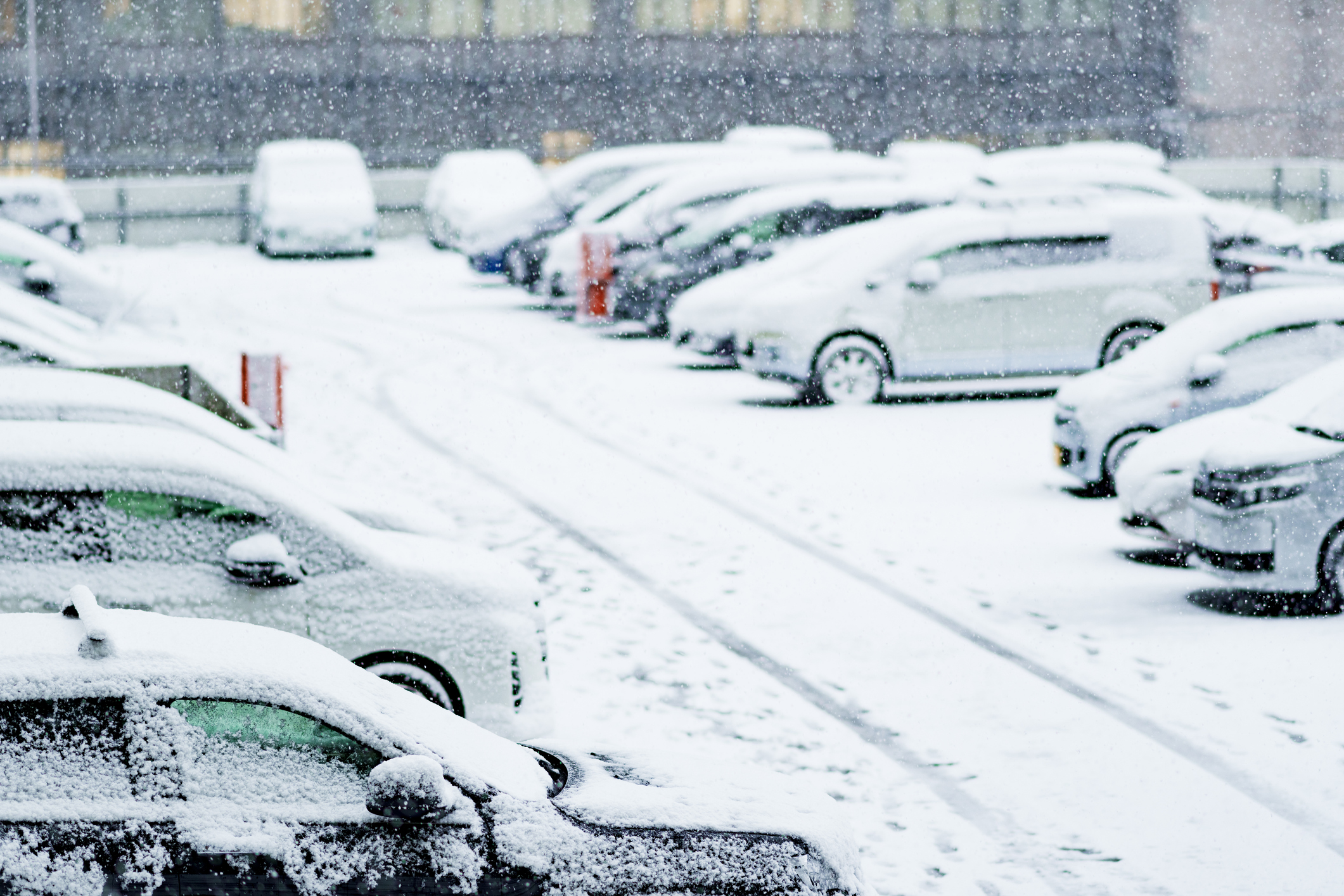 Snow-covered cars in a busy parking lot during winter, highlighting the need for reliable unattended parking payment systems.
