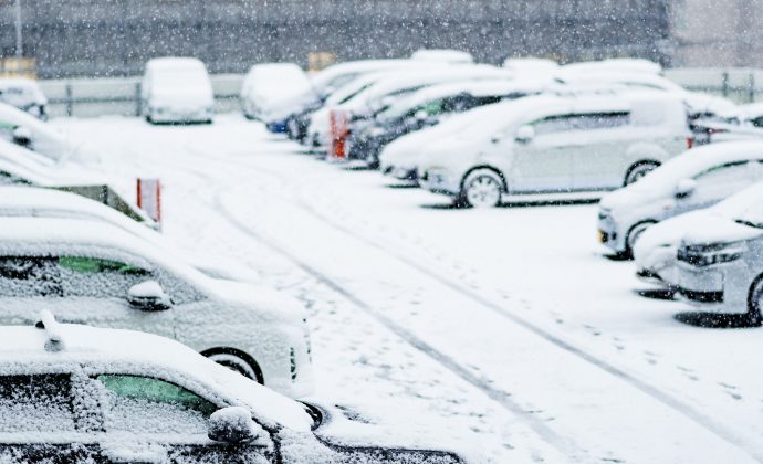 Snow-covered cars in a busy parking lot during winter, highlighting the need for reliable unattended parking payment systems.