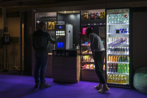 People buys food in micro market in night office Russia, Moscow - February 11, 2022: People buys coffee and food in micro market (unmanned self service smart store) in night office. Food service theme.