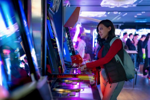 Young woman playing at a modern arcade game in a vibrant, cashless entertainment venue